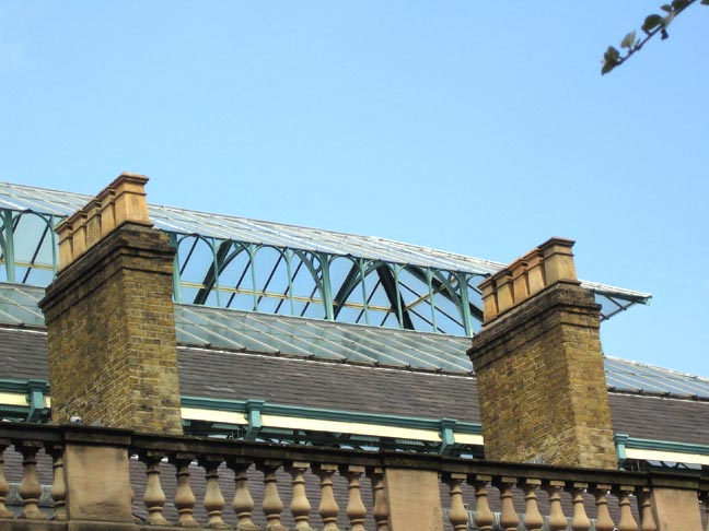 Central se eleva una porcin del techo de vidrio, con chimeneas de ladrillo en primer plano, Covent Garden, Londres